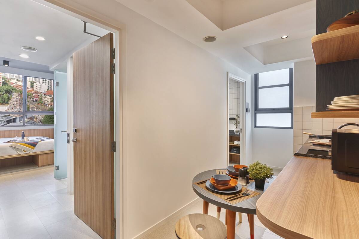 A modern kitchen with a round dining table, wooden cabinets, and a view of the city.