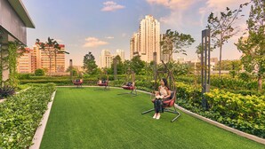 A rooftop garden with artificial grass, hanging chairs, and a view of surrounding high-rise buildings. - lyf Farrer Park Singapore (Singapore)