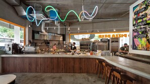 A modern cafe with a wooden counter, bar seating, and a neon light installation. - lyf Farrer Park Singapore (Singapore)