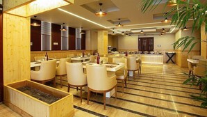 A restaurant with wooden paneling, multiple tables, and hanging pendant lights. - Lohmod Hotel (New Delhi)