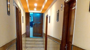 A hallway with marble flooring, wooden doors, and a staircase leading to an upper level. - Lohmod Hotel (New Delhi)