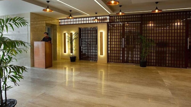 A modern lobby with a polished marble floor, a reception desk, and a decorative partition with vertical slats. - Lohmod Hotel (New Delhi)