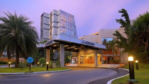 A hotel entrance with a modern design, featuring a prominent 'Le Meridien' sign, a covered walkway, and a landscaped area with palm trees. - Le Meridien Re-ndama (Libreville)
