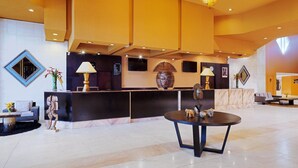 A lobby with a reception desk, a round table, and a seating area with a sofa and a chair. - Le Meridien Re-ndama (Libreville)