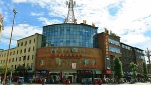 Un hotel con fachada de vidrio moderna, una estructura de antena destacada y un cartel que indica que es un hotel de 7 estrellas.