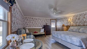Una habitación acogedora con cama, cómoda, sofá y una mesa con vasos y un florero.