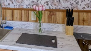 Una encimera de cocina con salpicadero de mármol, un bloque de cuchillos y un florero con flores.
