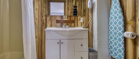 Une salle de bain avec un mur en bois, un lavabo blanc, un miroir, un téléphone et un porte-serviettes.