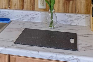 Un comptoir de cuisine avec un dessus en marbre, un téléphone intelligent et un vase contenant des plantes vertes.