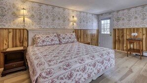 Un dormitorio con una cama grande, paneles de madera en las paredes y dos lámparas de pared.