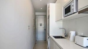 Une cuisine compacte équipée d’un lave-linge, d’un four à micro-ondes et d’un grille-pain, le tout posé sur le plan de travail.