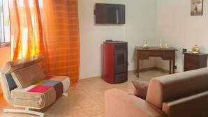 A living room with a sofa, a TV, a small table, and a heater.