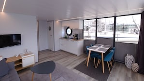 Um espaço de estar moderno e compacto, com cozinha, área de refeições e TV fixada na parede.