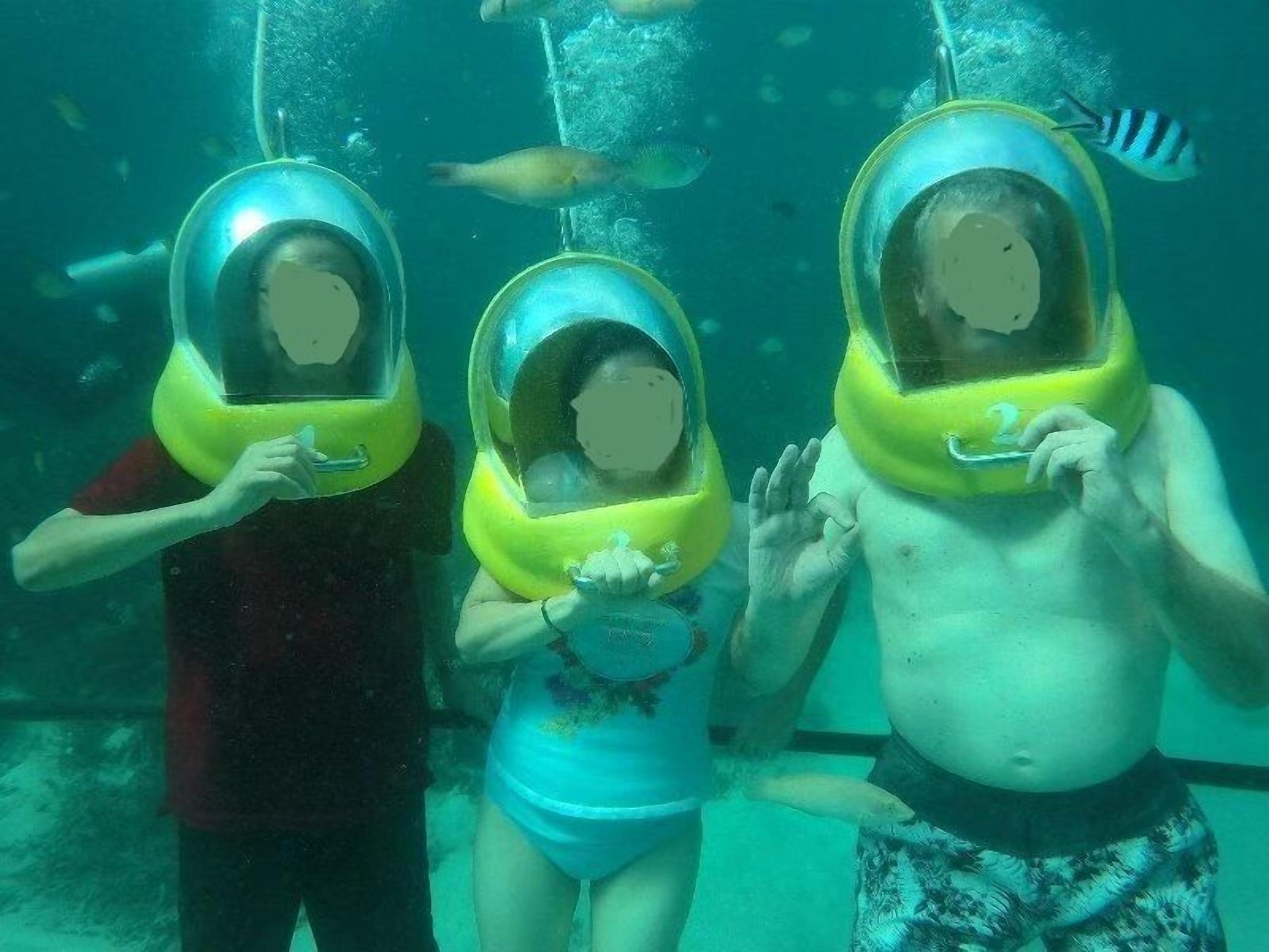 Three people wearing diving helmets underwater.