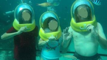 Three people wearing diving helmets underwater.