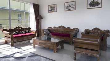 A spacious living room with a large window, two sofas, a coffee table, and a patterned rug.