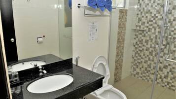 Une salle de bain avec un lavabo à vasque et un plan de toilette noir, des toilettes blanches et une douche à paroi de verre.