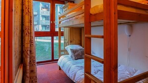 A bunk bed room with a large window, curtains, and a view of a building outside. - Ski-In/Ski-Out Apartment in Val Thorens - 6 Guests, Comfort Features, Central Location (Val Thorens)