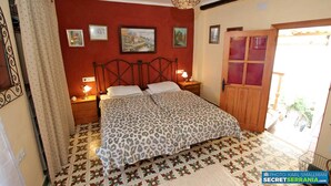 A bedroom with a bed, two bedside tables with lamps, a hanging light fixture, and a door with glass panels. - Immaculate House in Montejaque Sleeps 6 (Montejaque)