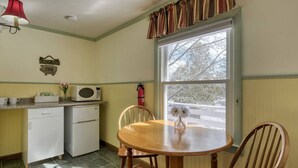 Una cocina acogedora con una mesa de comedor, sillas, microondas y refrigerador.