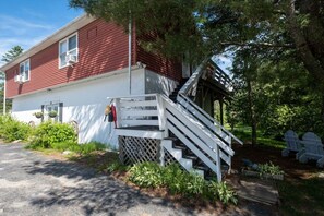 A red and white house with a white staircase leading to a porch.