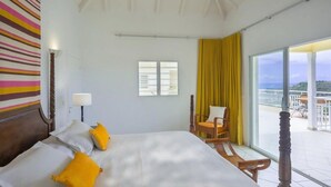 Un dormitorio con una cama grande, una ventana, un balcón con vistas y una pared a rayas.