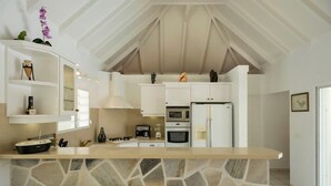 Una cocina moderna con gabinetes blancos, encimera de piedra y pared de piedra.
