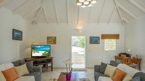 Una sala de estar con dos sofás, una mesa de centro, un televisor y una zona de comedor con una mesa y sillas.