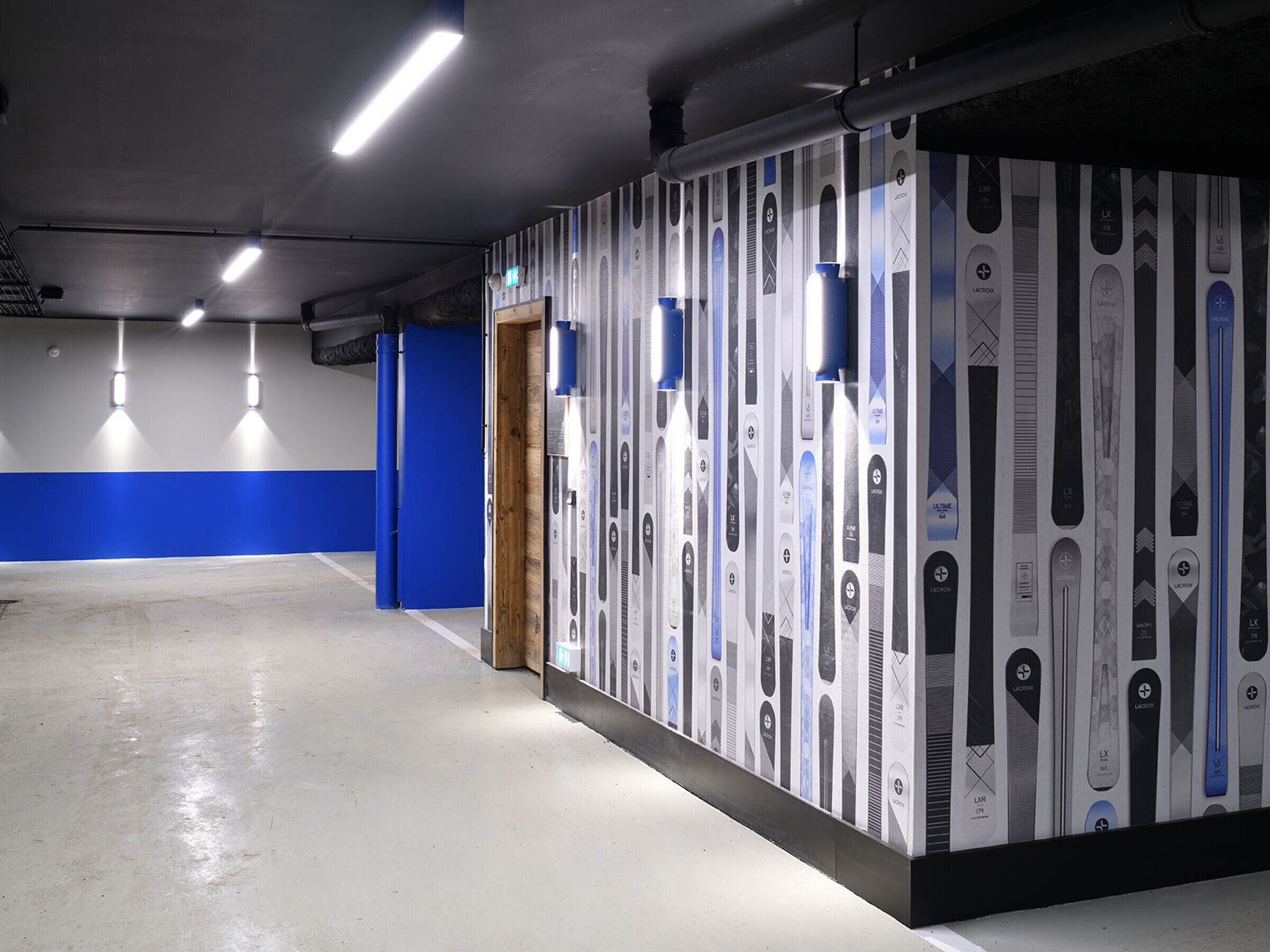 A modern indoor space with a concrete floor, blue walls, and a row of lockers with various designs.