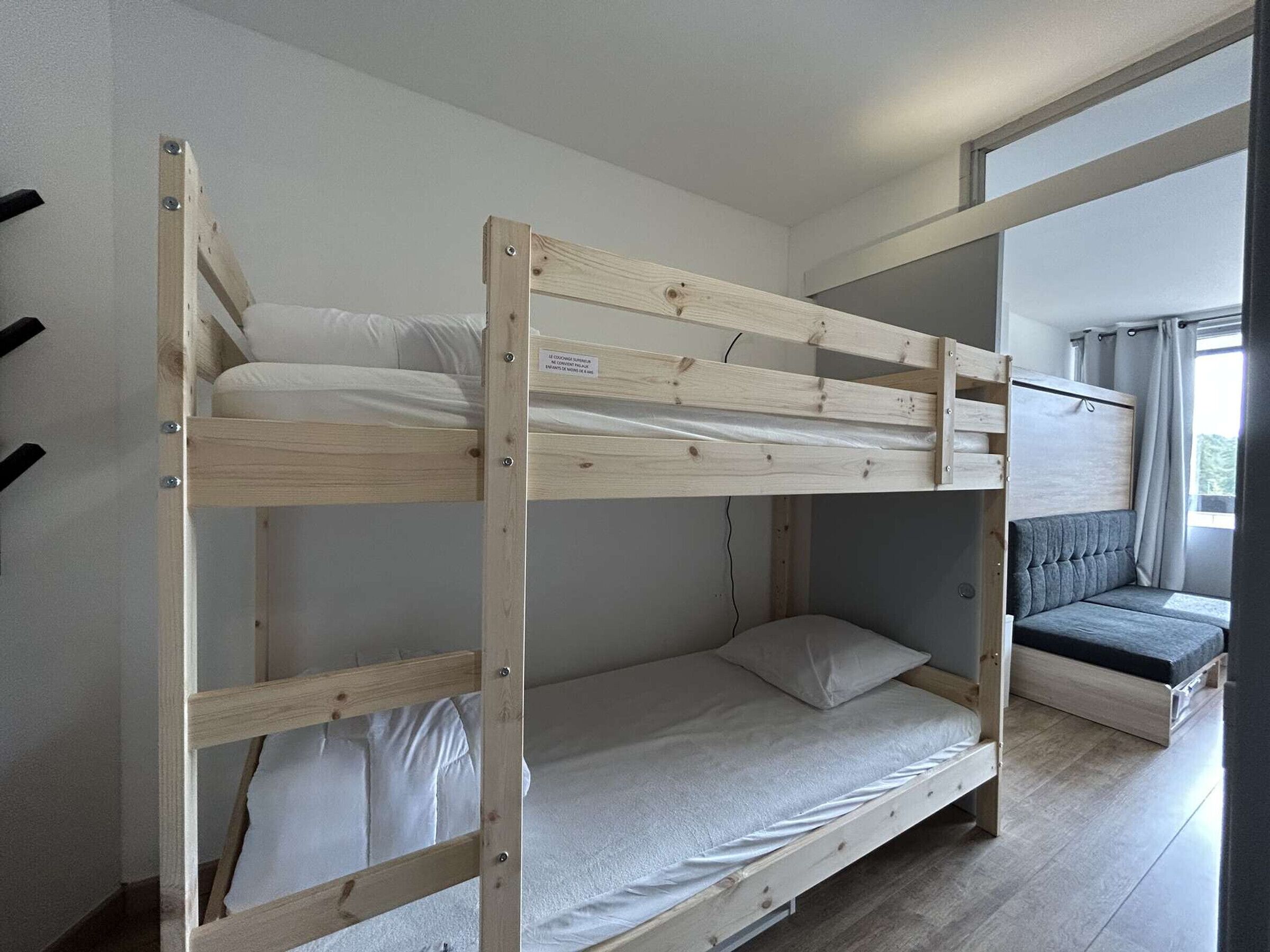En køjeseng med indbygget skrivebord og en polstret bænk.