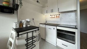 Une cuisine moderne avec des meubles blancs, un plan de travail noir et un four encastré.