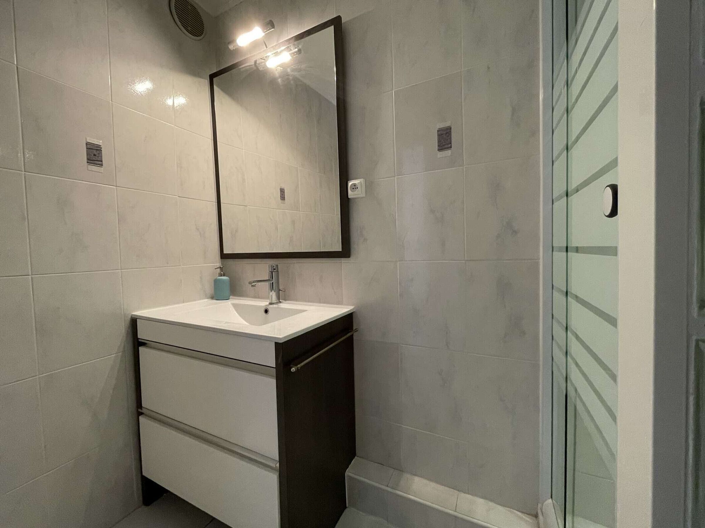 A modern bathroom with a white sink, dark vanity, and a large mirror.