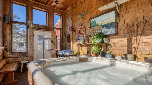 Een hottub in een rustieke blokhut met houten wanden, grote ramen en een schilderij erboven.