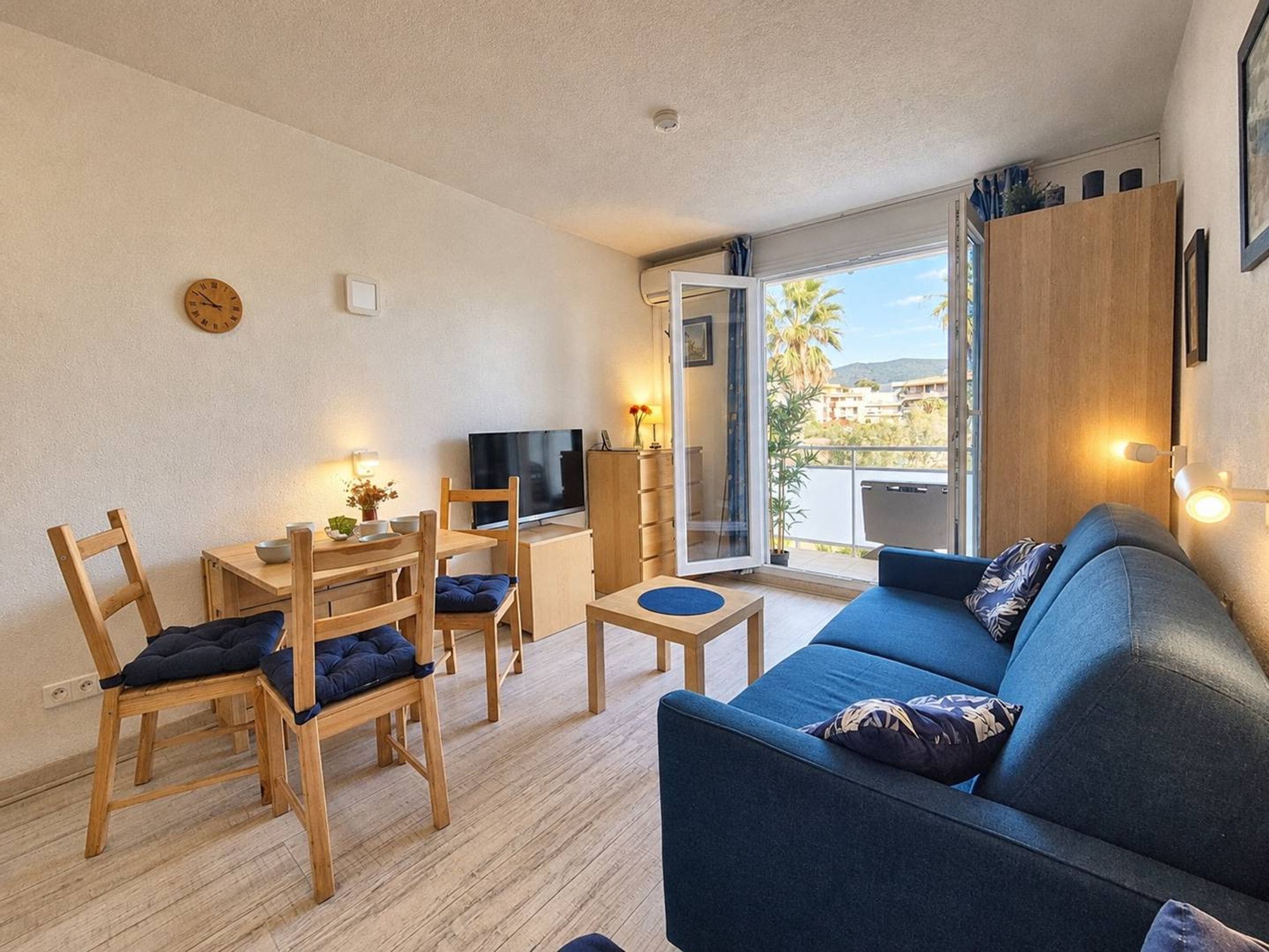 Un salon moderne avec un canapé, des fauteuils, un téléviseur et un balcon offrant une vue agréable.