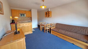 A compact living space with a kitchenette, a dining area, and a sofa. - Studio at the slopes with balcony, parking, 4 people (Les Deux Alpes)