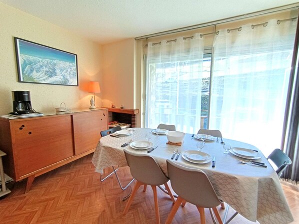 Een eetgedeelte met een tafel voor vier personen, een koffiezetapparaat, een lamp en een open haard.