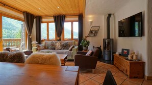 A cozy living room with a wooden ceiling, a fireplace, a TV, and a view of the outdoors. - Cozy chalet with mezzanine, wood stove, wifi and parking - Méribel (Méribel)