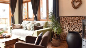 A cozy living room with a sofa, a coffee table, a potted plant, and a fireplace. - Cozy chalet with mezzanine, wood stove, wifi and parking - Méribel (Méribel)