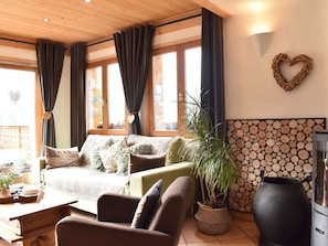 A cozy living room with a sofa, a coffee table, a potted plant, and a fireplace.