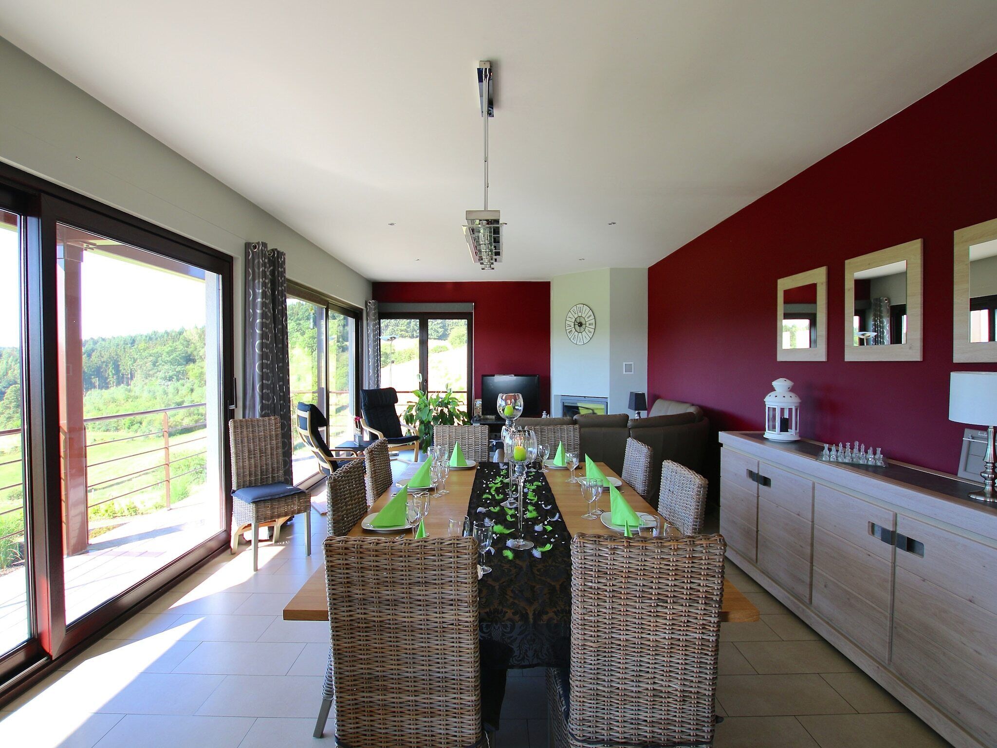 A dining area with wicker furniture, a long table set for six, and a view through large sliding glass doors.