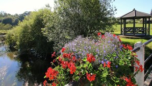 Ein Gazebo mit Metallgeländer, umgeben von üppigem Grün und verschiedenen Blumen.