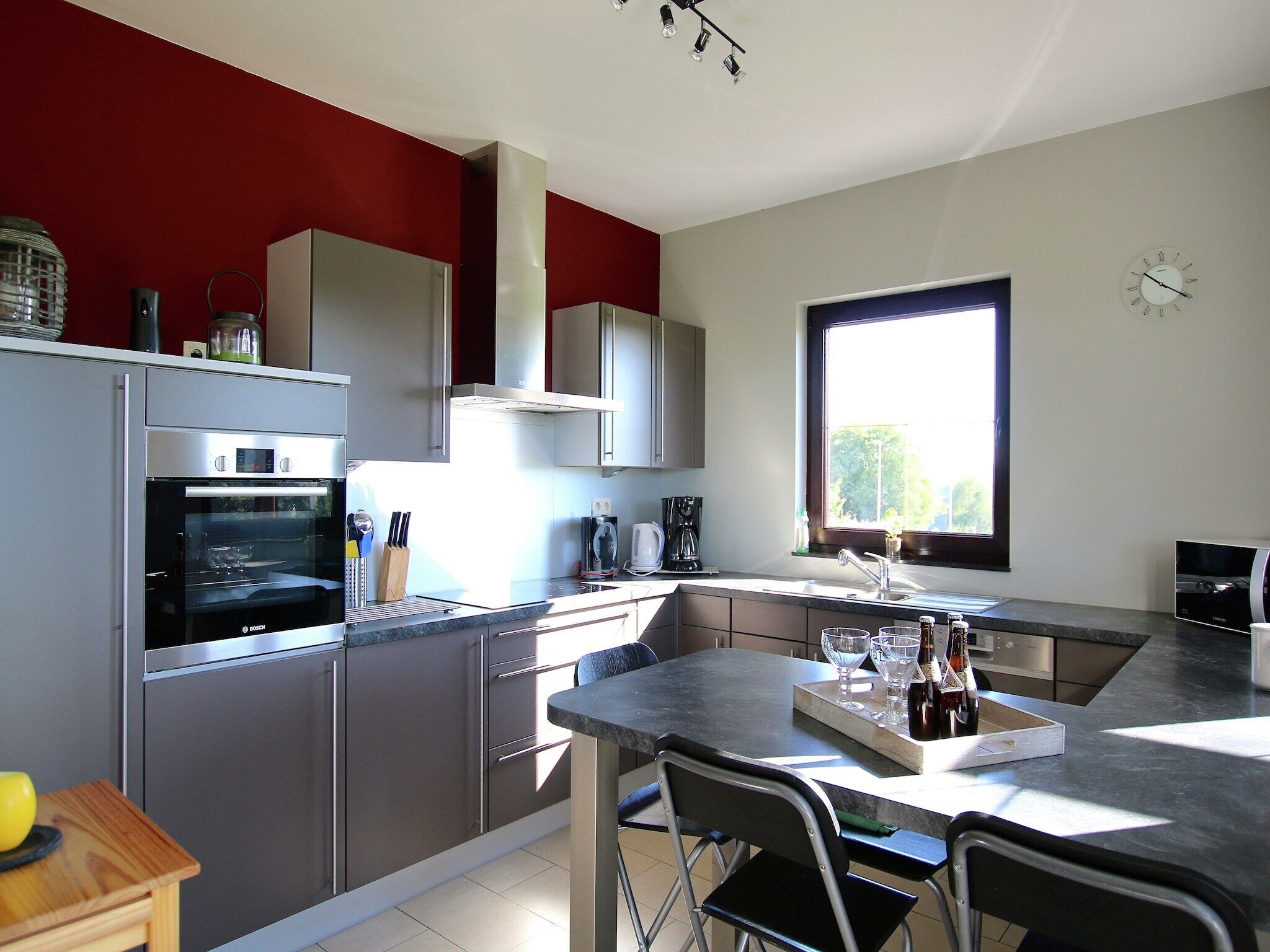A modern kitchen with stainless steel appliances, a dining area with a table and chairs, and a large window providing natural light.