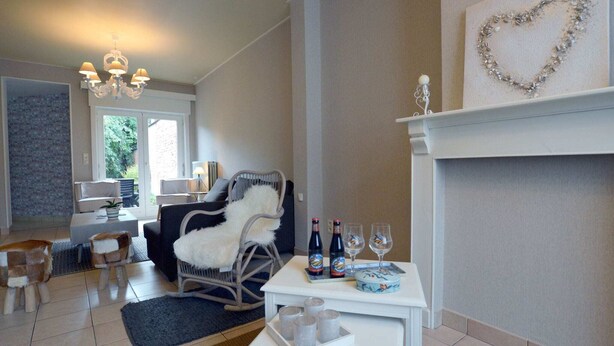 Ein gemütliches Wohnzimmer mit Kamin, einer Chandelüster und einem Essbereich mit Tisch für zwei Personen.