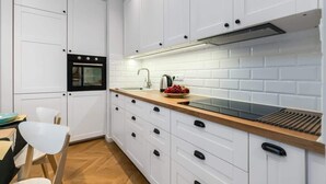 A modern kitchen with white cabinets, a built-in oven, a sink, and a wooden countertop.
