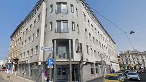 A multi-story building with a curved facade, a blue sign indicating 'Zentrum' and a distance marker '35m'. - Hauptbahnhof Boutique Rooms - Virtual Reception & Self-Checkin (Vienna)