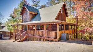 A log cabin with a porch, a staircase, and a small attached structure. - Enchanted Forest - Seasonal Mountain Views, Community Pool & Hot Tub (Sevierville)