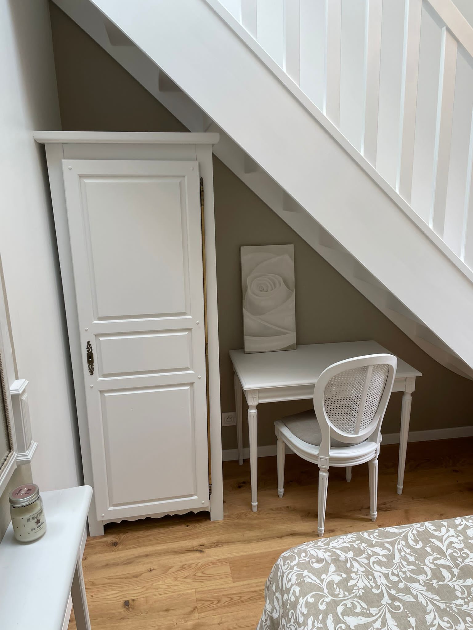 Een kamer met een wit bureau, een witte stoel, een witte garderobe en een trap.