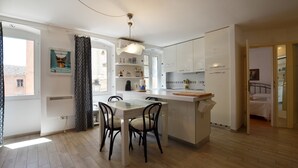 A modern kitchen with white cabinets, a central island, and a dining area with chairs. - Bea & Leo Apartment in center (Rovinj)
