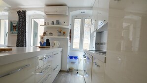 A modern kitchen with white cabinetry, a coffee machine, and a small island. - Bea & Leo Apartment in center (Rovinj)