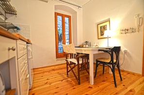 Una cocina pequeña con suelo de madera, una mesa de comedor, sillas y un ventanal con vistas.